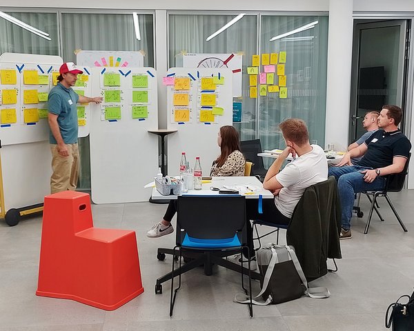 Lars Michaelis erklärt verschiedene Skizzen an einem Whiteboard vor einer Gruppe.